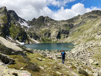 Rear view of people on rocks by mountains against sky