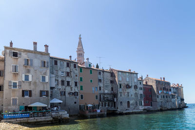 Buildings by sea against clear sky