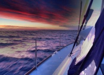 Cropped image of boat in sea at sunset