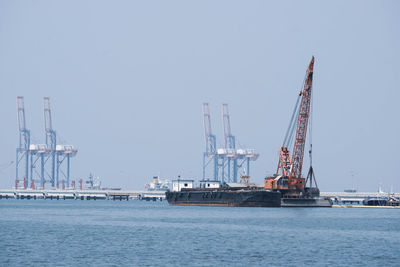 Cranes at commercial dock against clear sky