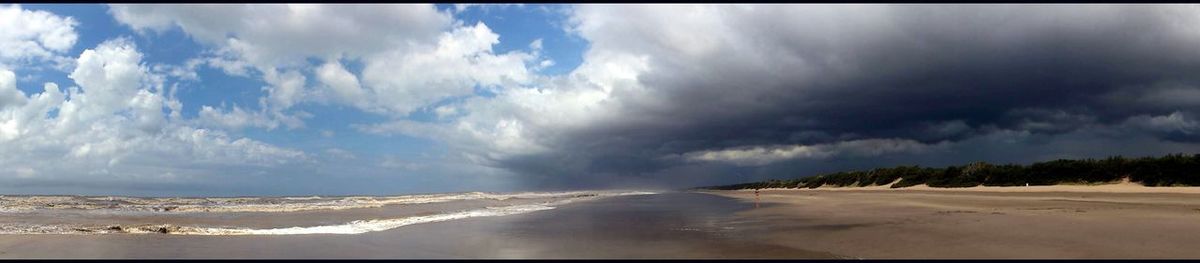 Scenic view of beach against cloudy sky
