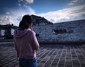 Rear view of woman looking at city against sky