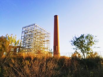 Low angle view of factory against clear blue sky