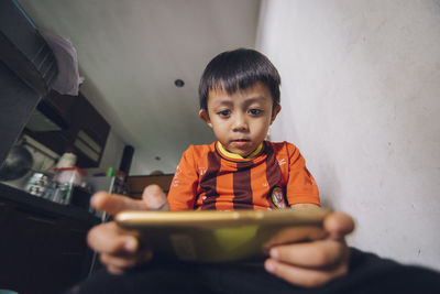 Cute boy using mobile phone at home