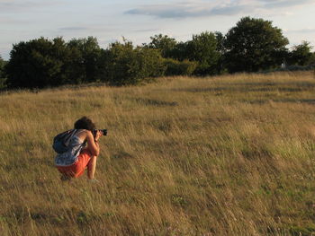 Woman photographing on field against sky