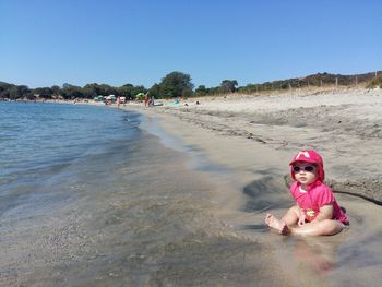 Portrait of happy girl on beach against clear sky