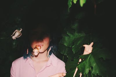 Close-up of girl with dolls amidst plants at night