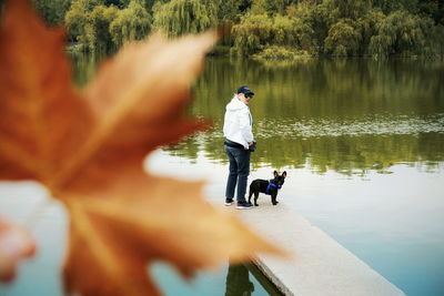 Full length of woman with dog standing on pier by lake