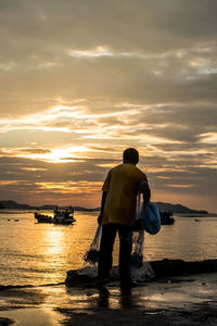Fisherman throwing net at jetty during sunset