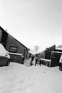 Snow covered houses by buildings against sky