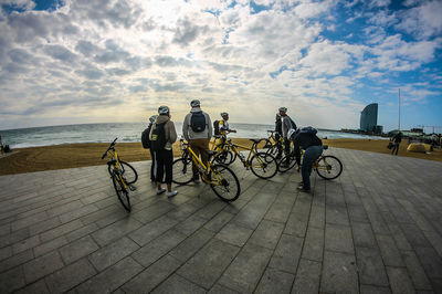 People on bicycle by sea against sky