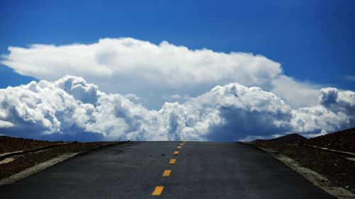 Scenic view of road by mountains against blue sky