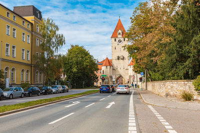 Cars on road by buildings in city against sky