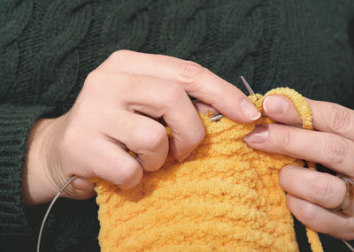 Woman hands knitting yellow scarf with needles. hand made accessories, knitted apparel. 