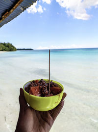 Person holding ice cream on beach