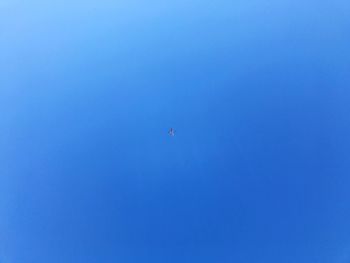 Low angle view of flying against clear blue sky