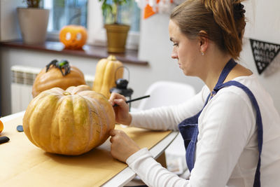 Side view of woman holding pumpkin