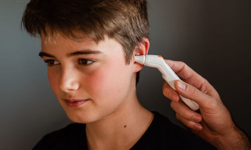 Tween boy getting temperature taken with an ear thermometer.