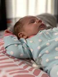 Portrait of cute baby girl sleeping on bed at home