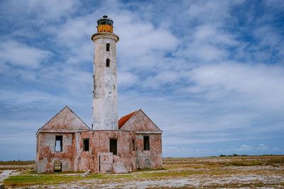 Old lighthouse amidst buildings against sky