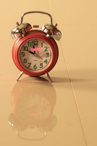 Close-up of clock on table against wall