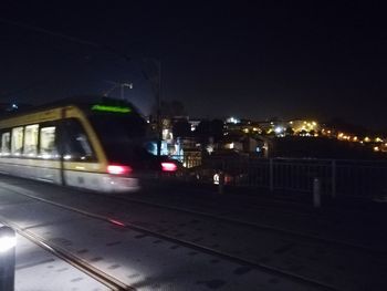 Illuminated railroad tracks against clear sky at night