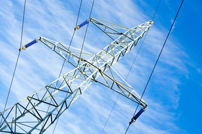 Low angle view of electricity pylon against blue sky