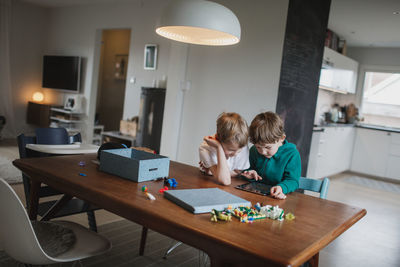 Boys sitting together at table and using digital tablet