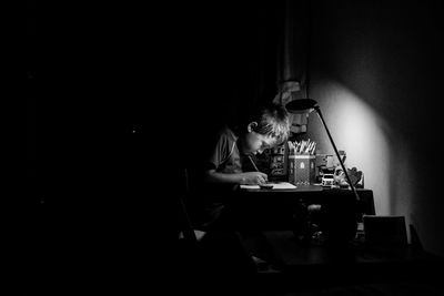 Side view of boy drawing at table