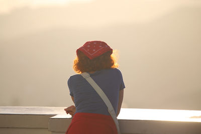 Rear view of woman standing by sea against sky