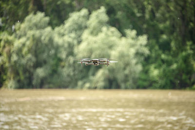 Airplane flying over river against trees