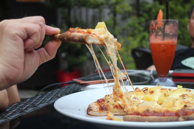 Cropped hand having pizza at table