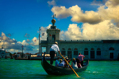 People on boat in sea against cloudy sky