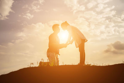 Silhouette friends standing against sky during sunset