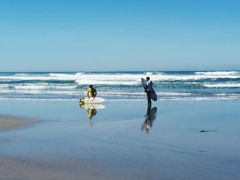 People on beach against clear sky