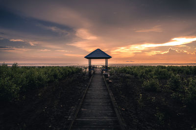 Lifeguard hut on land against sky during sunset