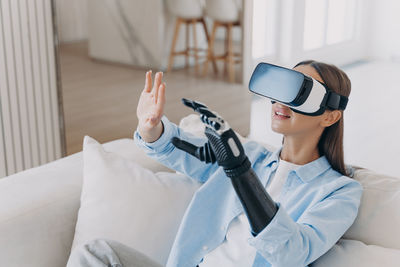 Young woman using mobile phone while lying on bed at home