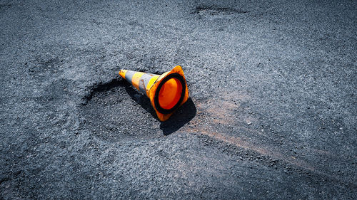 High angle view of orange traffic cone by hole on road