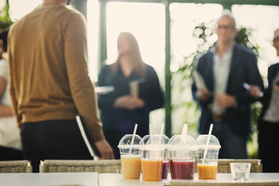 Fruit juice in plastic cups on table with business people in background at office