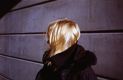 Side view of woman standing by wall