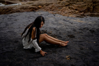 Side view of woman relaxing on sand at beach