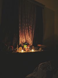 Illuminated tea light candles on table at home