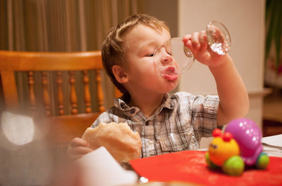 Cute boy drinking juice at home