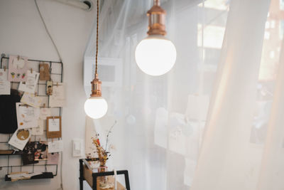 Illuminated light bulb hanging from ceiling