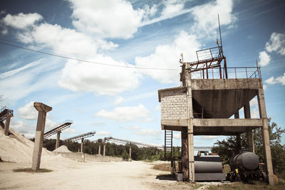 Low angle view of conveyor belt on sand pile at mine against sky