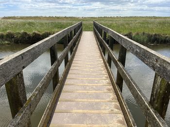 Beautiful landscape of wood bridge over water to huts and beach  sand dunes at walberswick suffolk