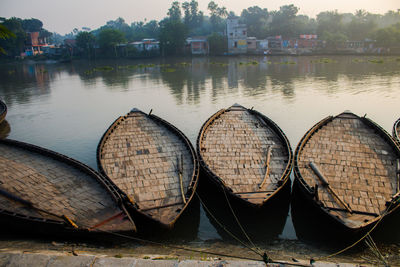 Boats moored on river by buildings against sky