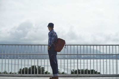Rear view of man standing on railing