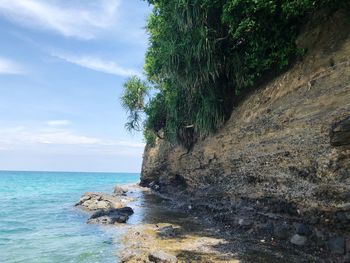 Scenic view of rocks by sea against sky