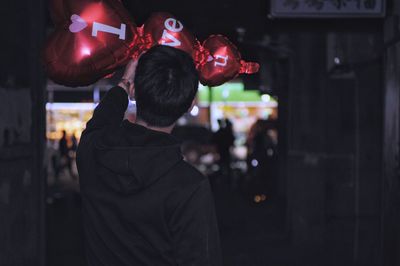 Rear view of man on touching decoration outdoors at night